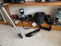 Wide shot showing tripod legs, Canon AE-1 with flash, Lowepro case, battery charger and STD-50 box