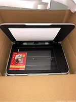 Canon Pixma MP620 all-in-one photo printer inside box with a pack of Canon Photo Paper Plus Glossy II 4x6" photo paper on the scanner glass.