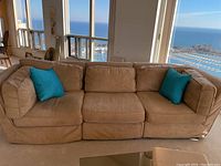 Front view of tan faux suede sectional with two blue accent pillows