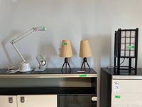 Five lamps displayed on a black table against a white wall