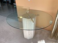 Full view of round glass table with extra square glass leaning against wall
