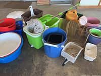 Overall lot showing multiple buckets, mop set, and various plant pots scattered on floor.