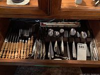 Wide shot of drawer with organized assorted wood-handled forks, Japanese cutlery, and other metal flatware.
