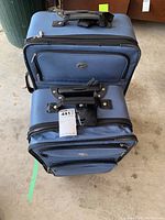 Two matching large blue softside suitcases stacked, visible front face showing zippers, handles, and fabric condition.
