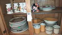 Image showing Mikasa Pastelle mugs with fruit patterns, beige and mustard colored stoneware bowls, plates with floral design stacked, and some unbranded stoneware pieces.
