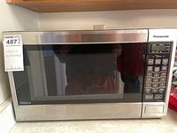 Front view of the Panasonic stainless steel microwave oven with digital control panel and black glass door.