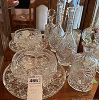 Overall view of the glassware set including the bowl, serving plate, and two decanters with stoppers placed on a mirrored surface