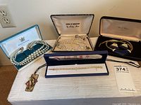 Overview photo showing all jewelry items including pearl necklaces, Swarovski bracelet in box, and other necklace and bracelet sets.