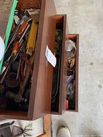 Top view of three wooden drawers containing various hand tools and hardware accessories showing mixed contents including tools with wooden handles and small hardware parts.