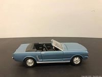 Side profile of light blue 1964 Mustang convertible diecast model with closed doors and hood.