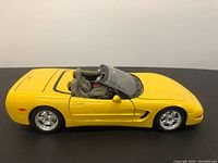 Front angled view of yellow Burago Chevrolet Corvette C5 diecast car model showing side and interior seats.