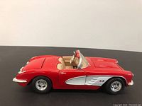 Side view of red diecast convertible car model showing smooth exterior, chrome accents, and interior upholstery.