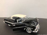Side front view showing the black and cream white two-tone paint, open hood revealing engine details, and front door open revealing interior seat.