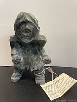 Overall front view of the signed Native Inuit carved statue with certification tag attached.
