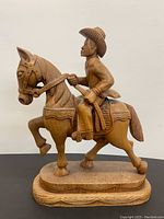 Full view of the wooden cowboy figurine on a horse, showing overall size and shape.