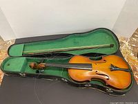 View of vintage violin and bow inside green-lined violin case