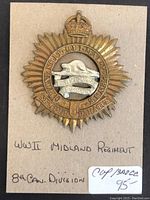 Front view of the vintage WWII Midland Regiment cap badge showing the sunburst design with crown and central beaver motif with text.