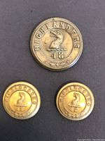 Three vintage brass buttons with 'HIGHLANDERS' and '48' text and bird emblem, displayed on black background.