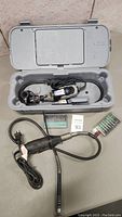 Two Dremel rotary tools in plastic carrying cases with cords, flex shafts, and accessory kits.