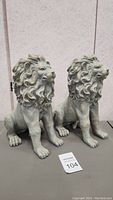 Front view of two resin lion statues sitting side by side, showing detailed mane and facial features.