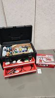 Photo of the opened toolbox showing multiple bottles of paint, brushes, and airbrush supplies in red drawers.
