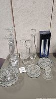 Photo showing six crystal decanters and two round crystal bowls on table.