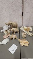 Overview of all 9 marble animal figurines including elephants, lion, whale, turtle, bird, and other small animals on a gray table.
