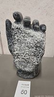 Front view of marble hand statue showing rough central area and polished fingers