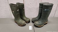 Pair of olive green rubber steel toe work boots seen from front angle showing overall shape and condition.