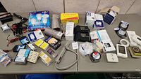 Overview of table with various tools and home repair electrical items including bulbs, outlets, power strips, tape, and timer.