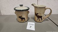 Front view of the cream and sugar set showing the moose designs