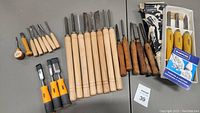 Full lot overview of multiple wood carving chisels with wooden and rubber handles, boxed set, manuals