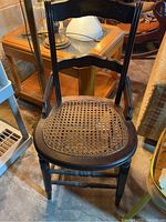 Antique wooden chair with cane woven seat and carved decorative backrest in used condition.