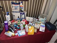 Table with multiple personal care, medical, and bathroom items including bottles, sprays, cotton pads, and boxes.