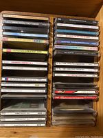 Photo showing two stacks of CDs arranged in a wooden shelf, featuring titles like Gershwin Greatest Hits, Neil Diamond, and multiple Christmas music CDs.
