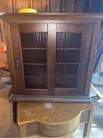 Wooden cabinet with sliding lattice doors sitting on top of Philco table with curved front edge.
