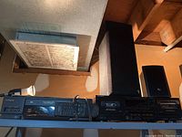 Photo of Hitachi stereo receiver, Sony cassette player, two Sony speakers, and wired remote control on a metal shelf.