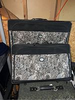 Two matching floral pattern rolling suitcases stacked, showing front panels and zippered compartments