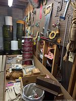 Wide view of lot showing stacked metal cans, wooden boxes, small hardware items, and tools organized on pegboard.