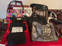 Photo of assorted purses and handbags on a flat surface showing different colors and styles including metallic, patterned, and leather bags.