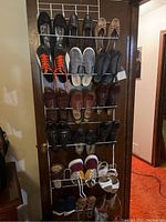 Full view of shoe rack holding multiple pairs of men's and women's shoes of various styles and colors