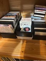 Photo showing organized VHS tapes and some CD cases on a wooden shelf surface