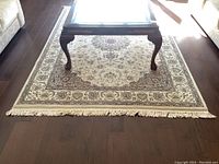 Overall view of rug under coffee table on hardwood floor showing full pattern and size