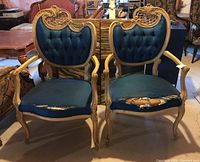 Two Rococo style arm chairs with blue tufted fabric backs and seats, ornate carved wooden frames, and visible tear damage on seat fabric.