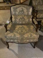 Front view of armchair showing full upholstery pattern and carved wood frame