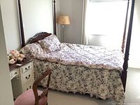 Four-poster wood bed with floral bedding.