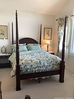 Full view of the bed setup with floral bedding in a bedroom.