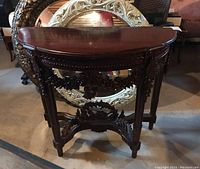 Front view of the demi-lune table showing semi-circular top and carved embellishments