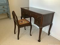 Desk and chair side angle showing the wood finish, drawer fronts, and cane seat condition.