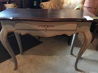 Front view of the Ethan Allen wooden desk with one drawer, showing the grey and gold hand-painted finish and curved legs.